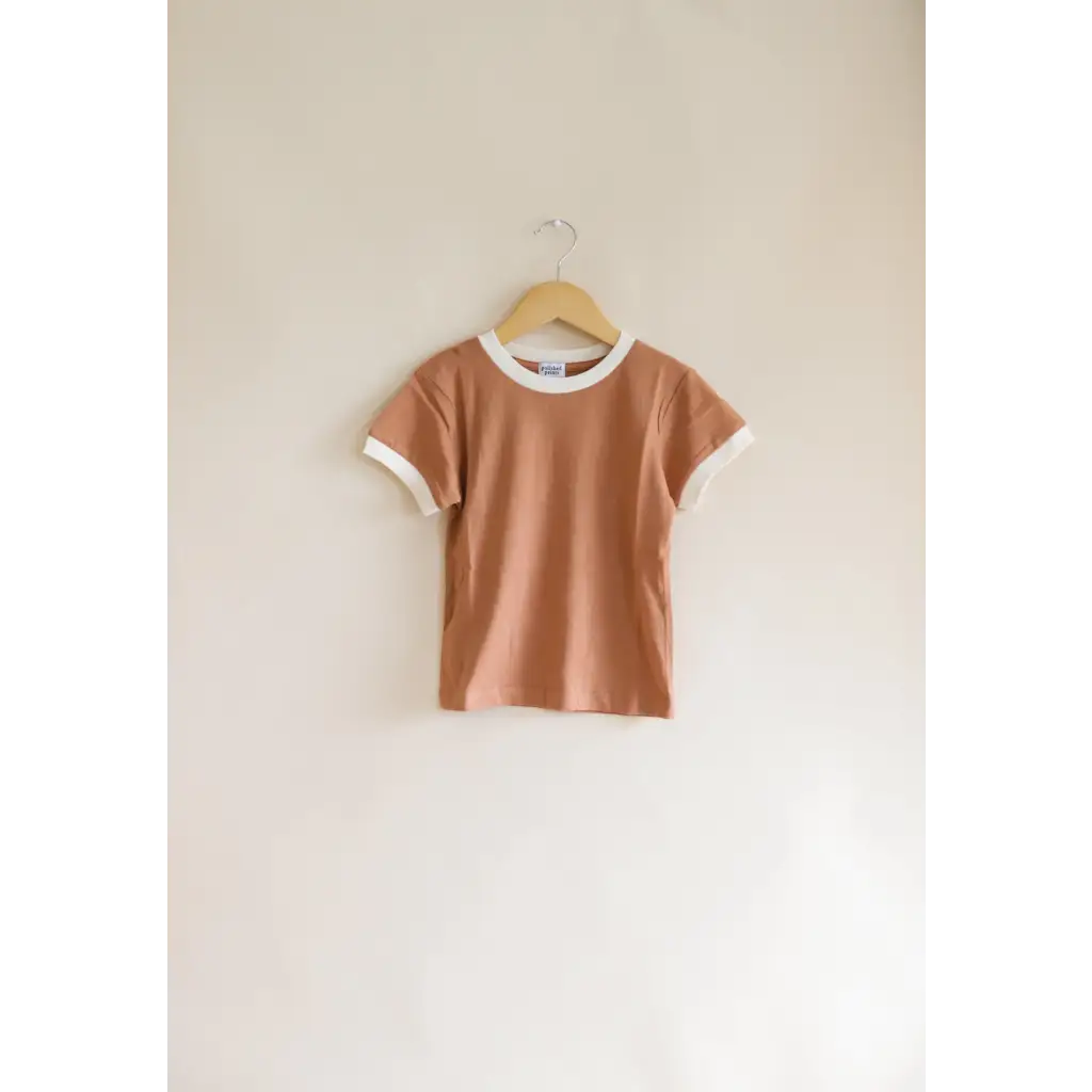 Peach Everyday Ringer Tee with White Trim hanging on a hanger for kids