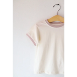 White Everyday Kids Ringer tee with pale pink trim hanging on a wooden hanger