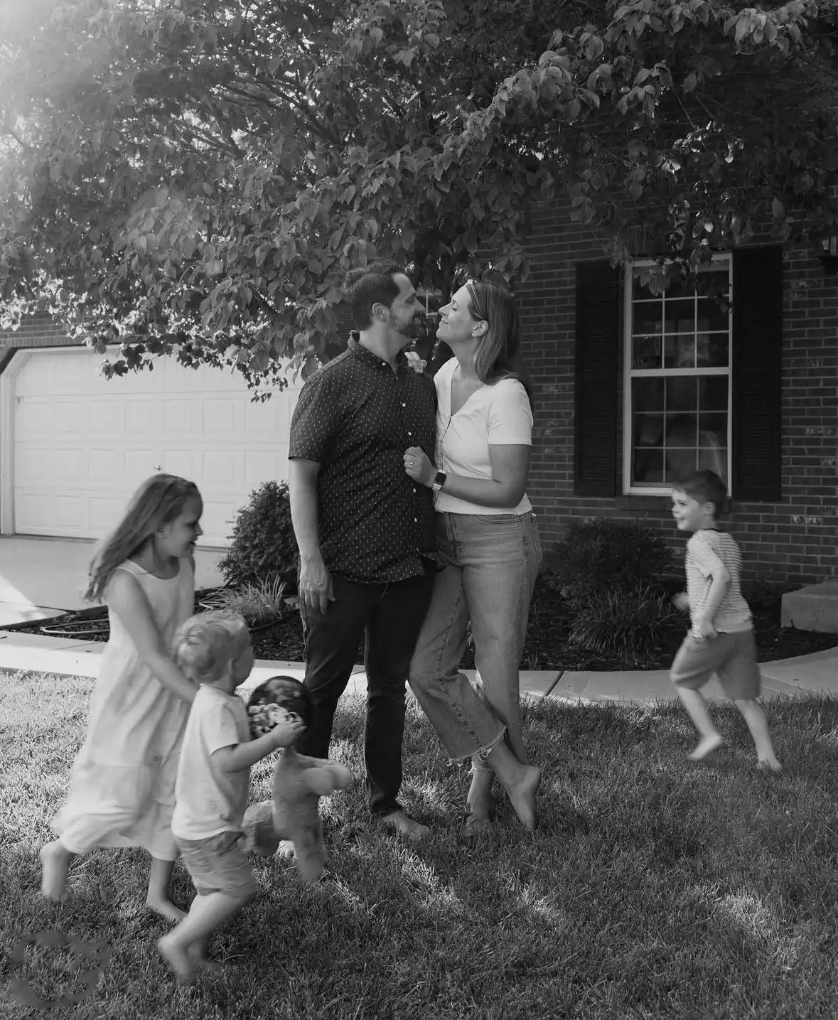 A family enjoying a playful moment together on their lawn.