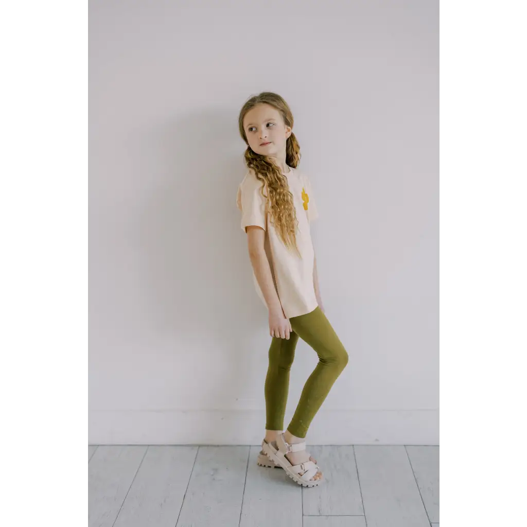 Person rocking flexible lightweight olive green leggings with a cream shirt and platform sandals