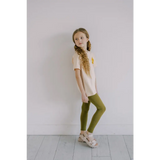 Person rocking flexible lightweight olive green leggings with a cream shirt and platform sandals