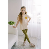 Child in cream top and olive green leggings, rocking Good Vibes Flexible Lightweight Leggings