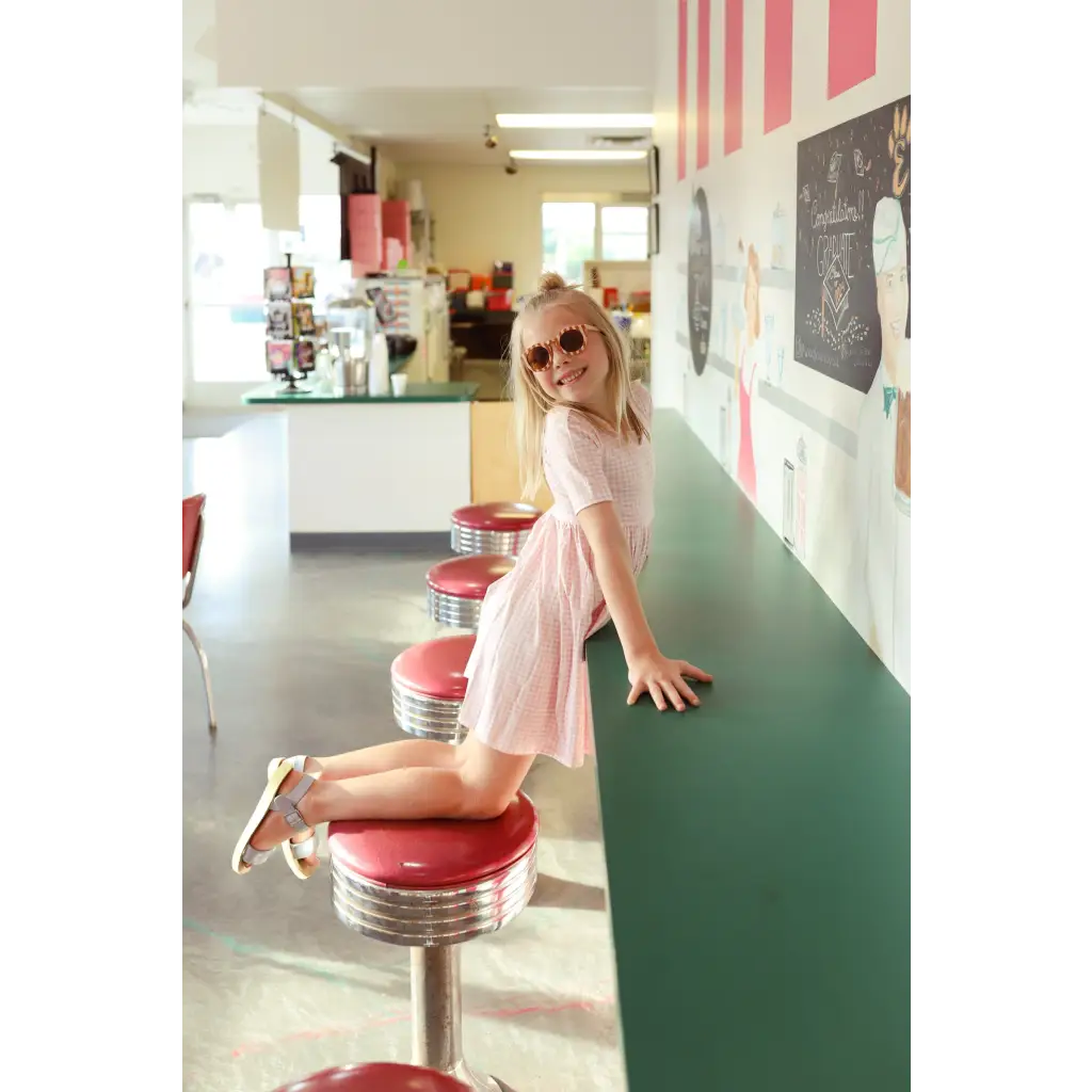 Pink Gingham All Day Twirl Dress with sunglasses at a retro diner counter