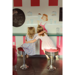 Kids rocking a Gingham All Day Bamboo Twirl Dress at a retro diner counter