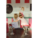 Kids rocking a Gingham All Day Bamboo Twirl Dress at a retro diner counter