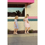 Two young girls in summer gingham dresses enjoying a stylish stroll on the sidewalk