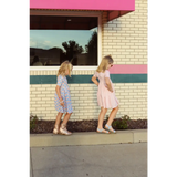 Two young girls in summer gingham dresses enjoying a stylish stroll on the sidewalk