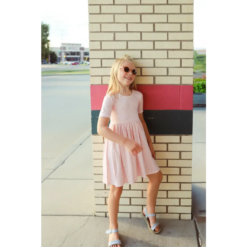 Cute pink gingham dress with gathered waist, perfect for stylish kids. Polished prints!