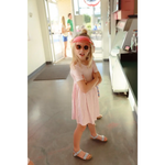 Child in pink Gingham dress, stylish sunglasses, and sandals for fun summer vibes