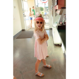 Child in pink Gingham dress, stylish sunglasses, and sandals for fun summer vibes