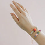 Gold pull-tie beaded bracelets with colorful pastel, orange and striped beads