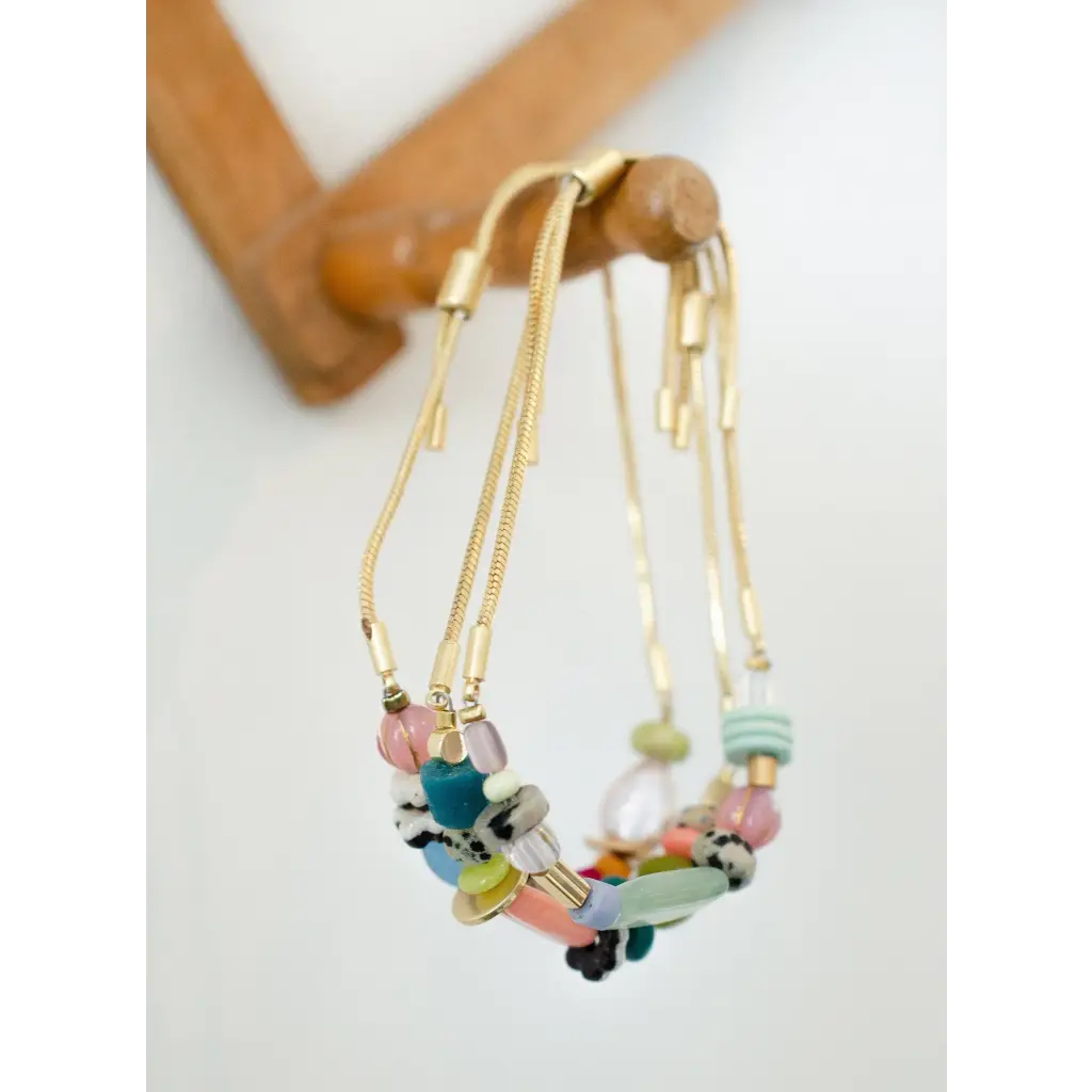 Colorful gold pull tie beaded bracelet with pastel hues and metal accents