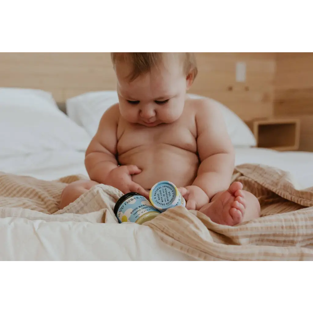 Baby checks Good Baby organic honey jars on bed for chapped cheeks balm