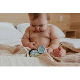 Baby checks Good Baby organic honey jars on bed for chapped cheeks balm
