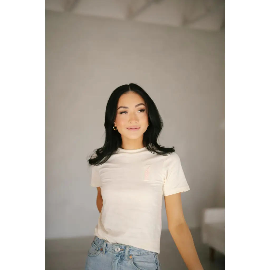 Someone in a white Vibes Peace Embroidered Tee and light blue jeans spreading good vibes peace