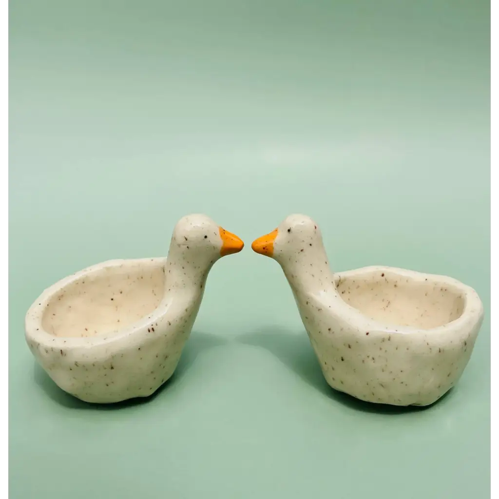 Two speckled off-white ceramic goose ring dishes with orange beaks
