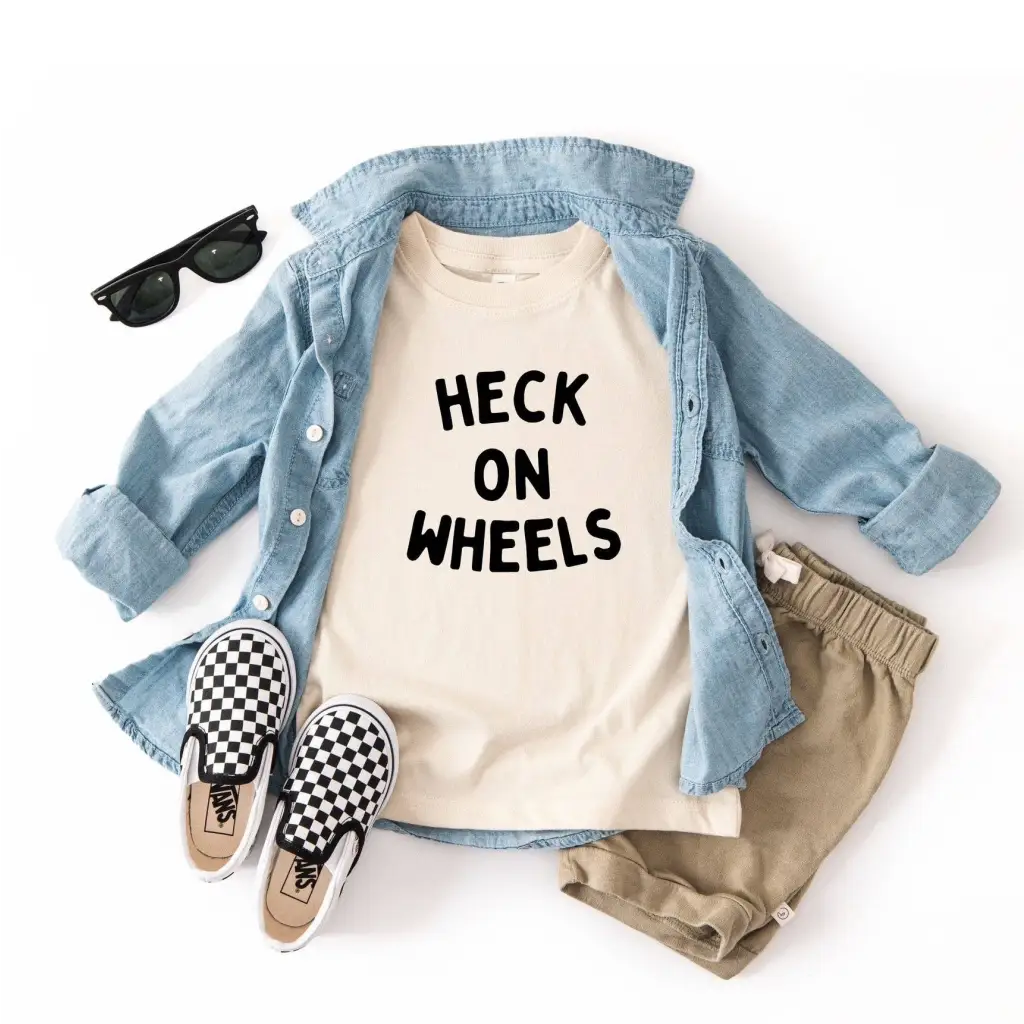 Cute kid’s outfit with a light blue shirt, cream tee, khaki shorts, and checkered slip-ons