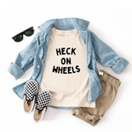 Cute kid’s outfit with a light blue shirt, cream tee, khaki shorts, and checkered slip-ons