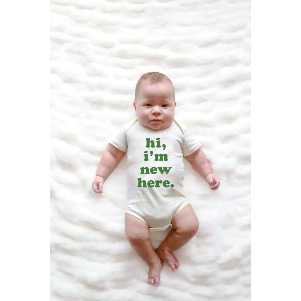 Baby wearing a Hi I’m New Here Baby Onesie in Organic Cotton Sage with green text