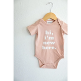 Pink baby onesie on a hanger from Hi, I’m New Here in soft organic cotton