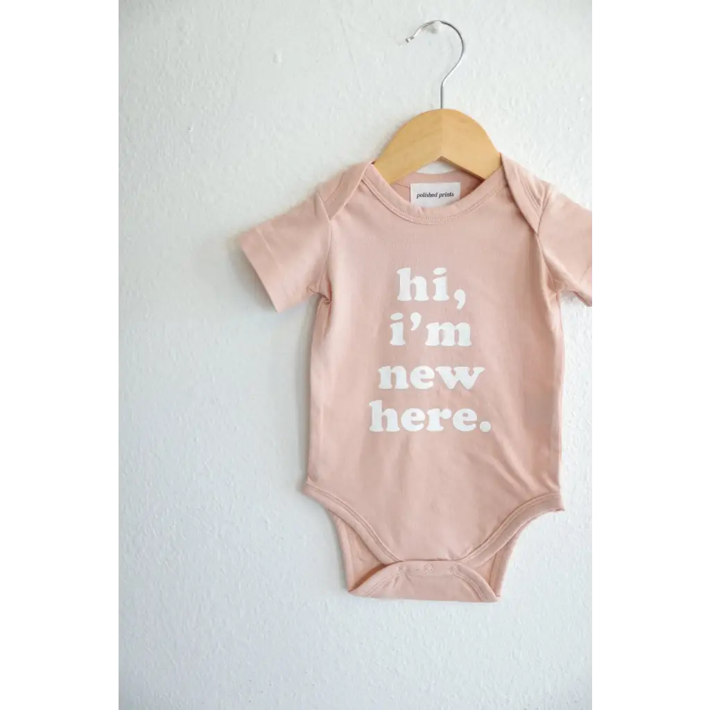 Pink baby onesie on a hanger showcasing stylish organic cotton and polished prints