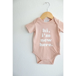 Pink baby onesie on a hanger showcasing stylish organic cotton and polished prints