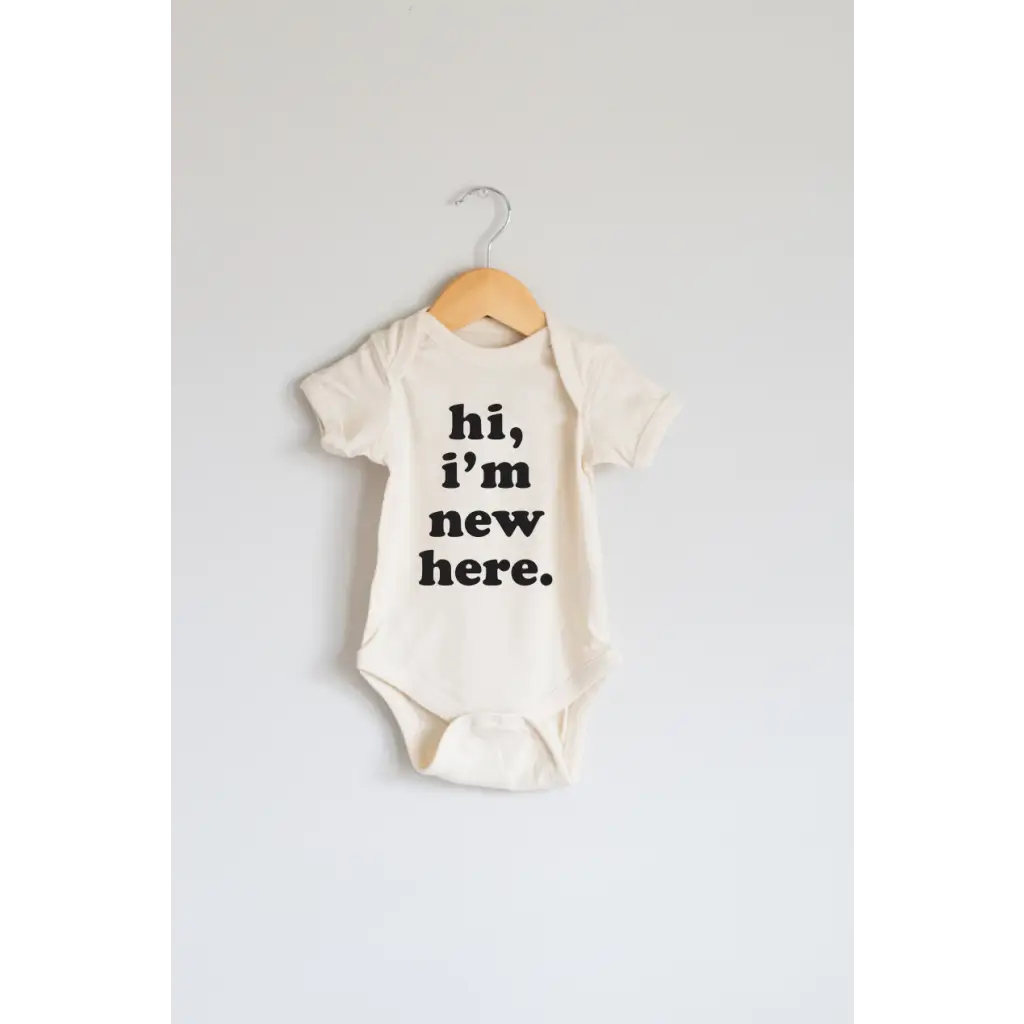 White organic cotton baby onesie with Hi, I’m New Here print in black letters