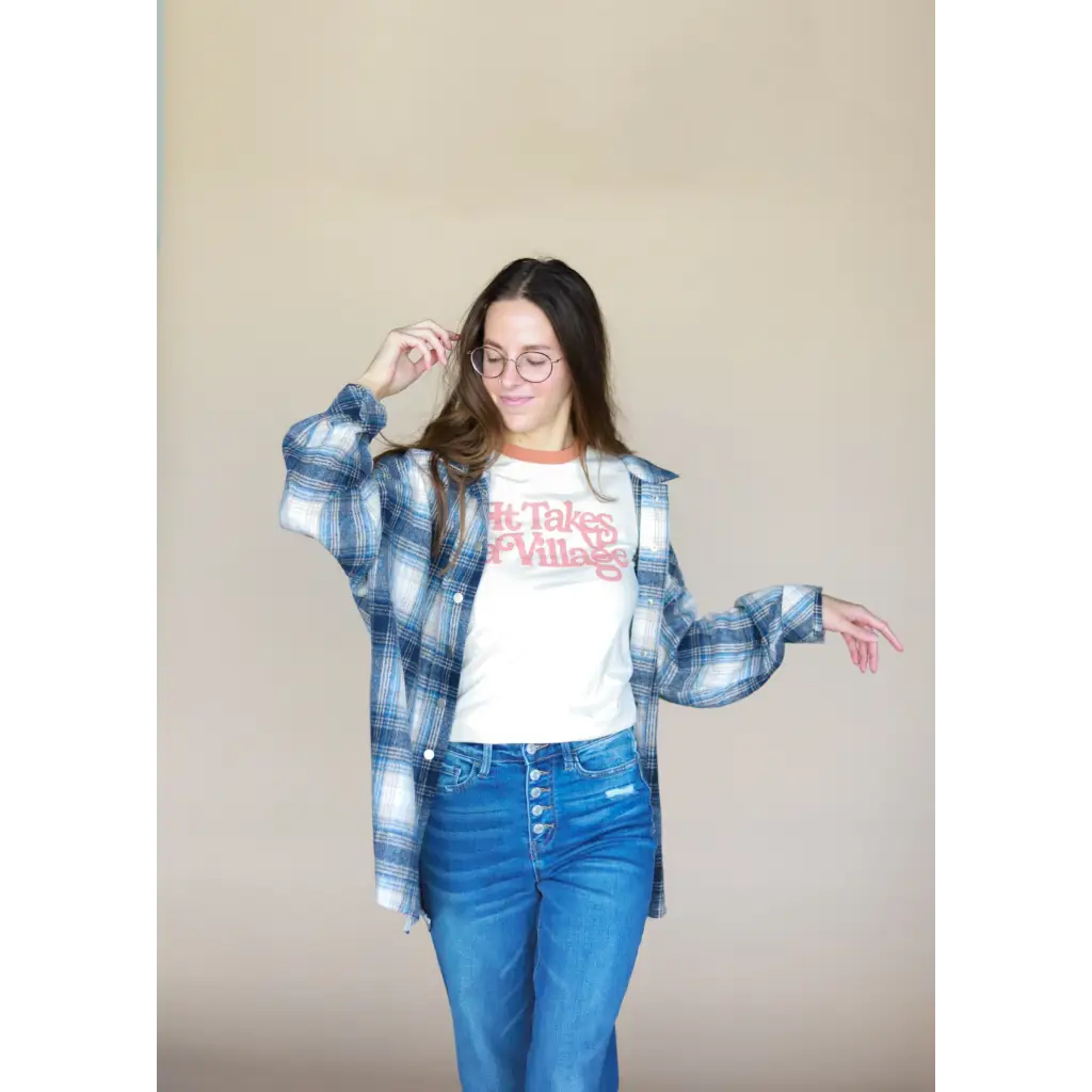 Person in plaid shirt over It Takes a Village Adult Retro Ringer Tee and blue jeans