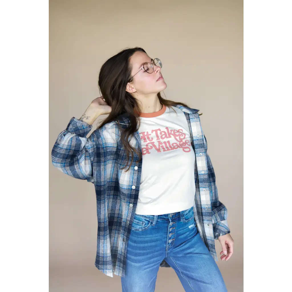 Blue plaid flannel over a white graphic tee and jeans for the It Takes a Village Adult Retro Ringer