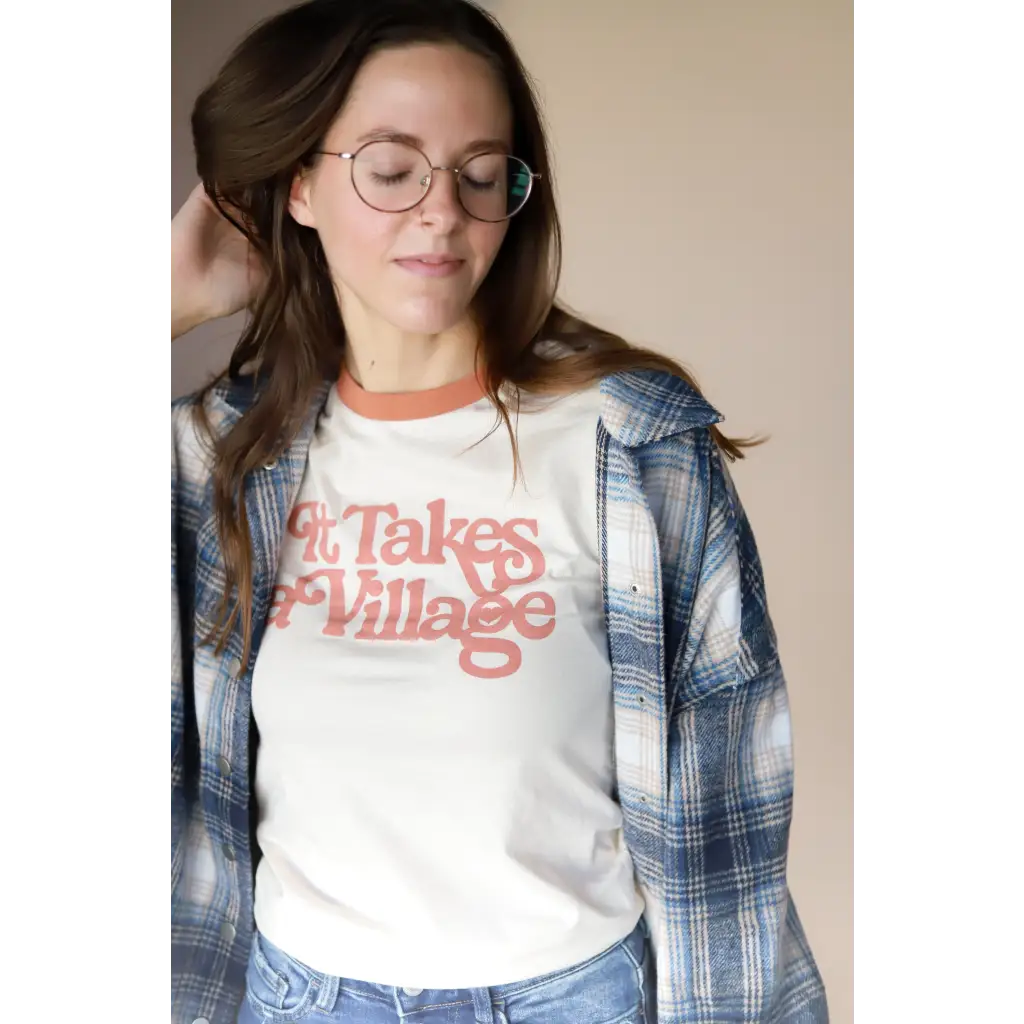 White retro ringer tee with Takes Village graphic under blue plaid flannel shirt