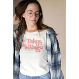 White retro ringer tee with Takes Village graphic under blue plaid flannel shirt