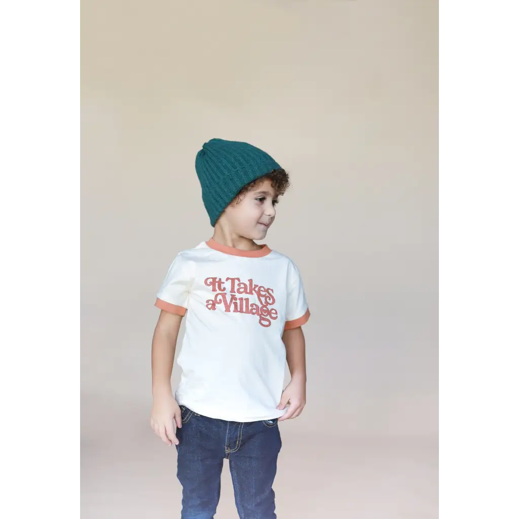 Child in a white ringer tee, blue jeans, and teal beanie rocking stylish vibes