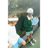 Two kids in sneakers by a fence showing off their mini pickle ball paddles