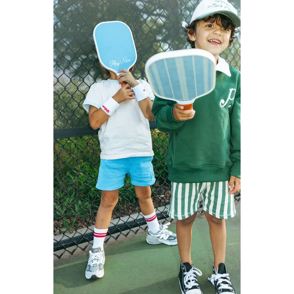 Two kids playing on a court with mini pickle ball paddles, starting em’ young!