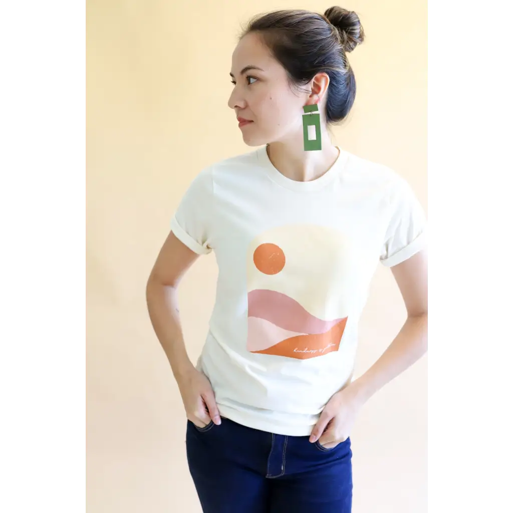 White Golden Relaxed Graphic Tee with minimalist sunset design and green earrings