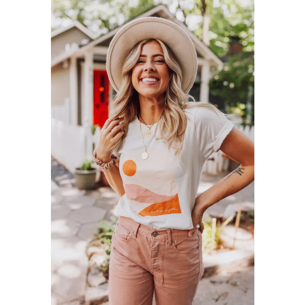 Joyful person in a wide-brimmed hat rocking the Golden Relaxed Graphic Tee and pink pants