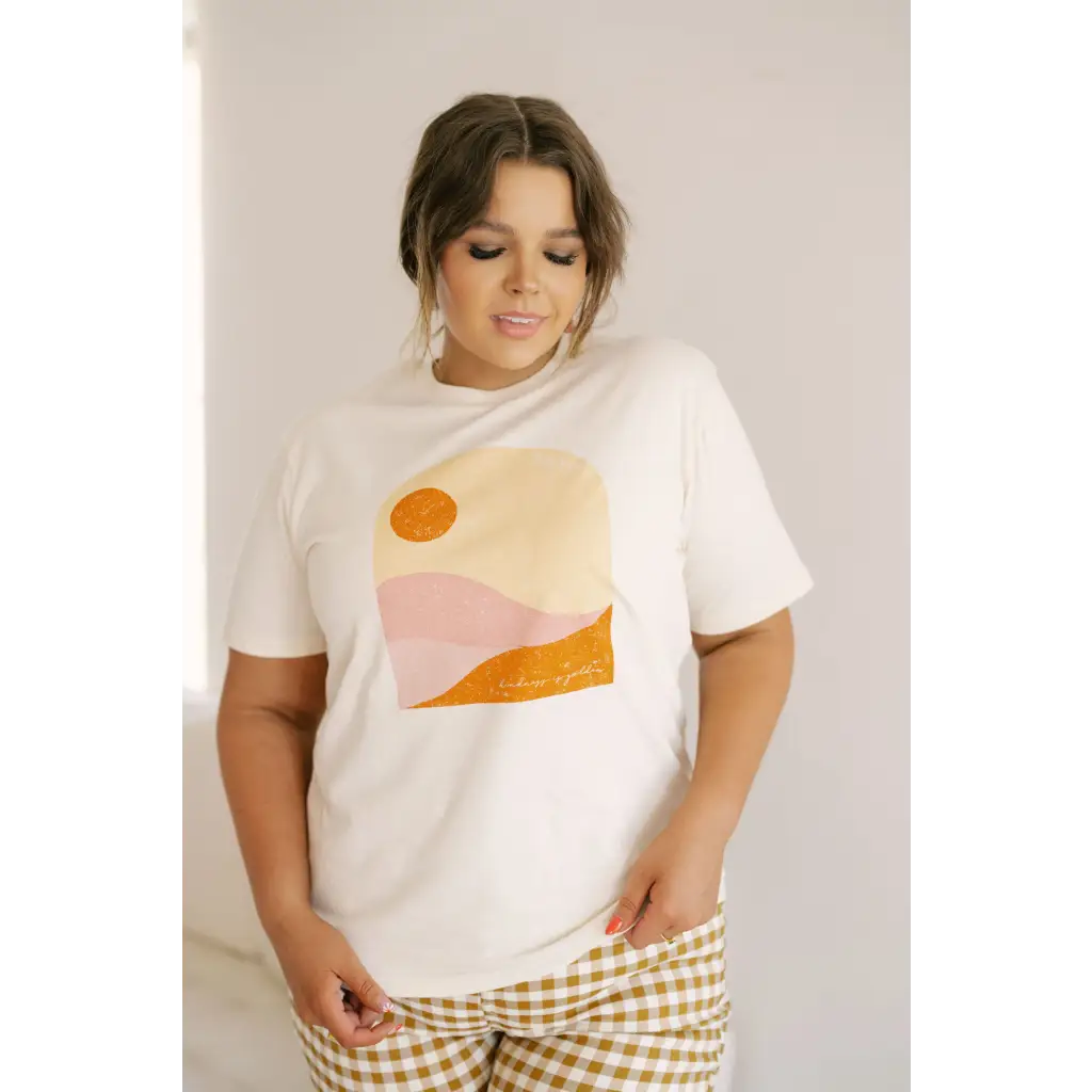 White graphic tee with a minimalist sunset design in orange and pink tones