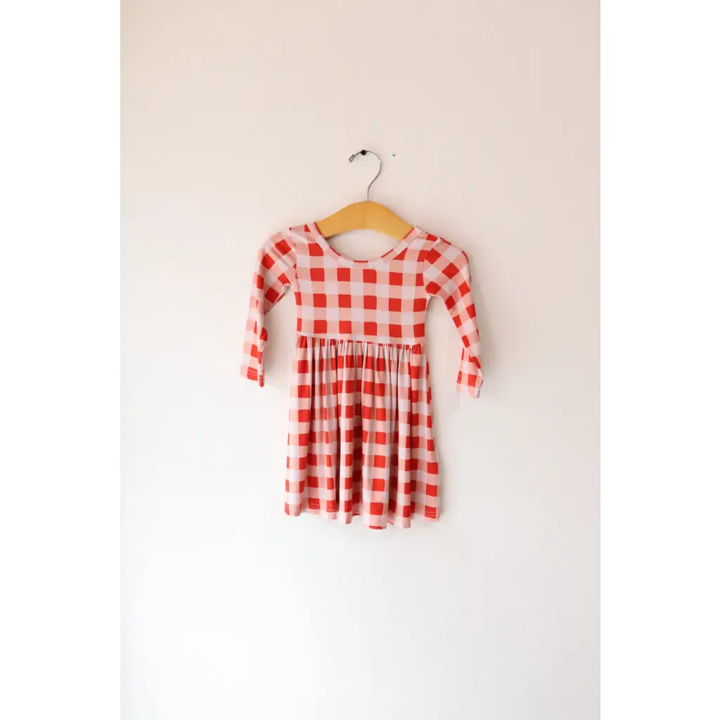 Cute red and white gingham Kit Plaid Dress hanging on a wooden hanger, perfect for twirling