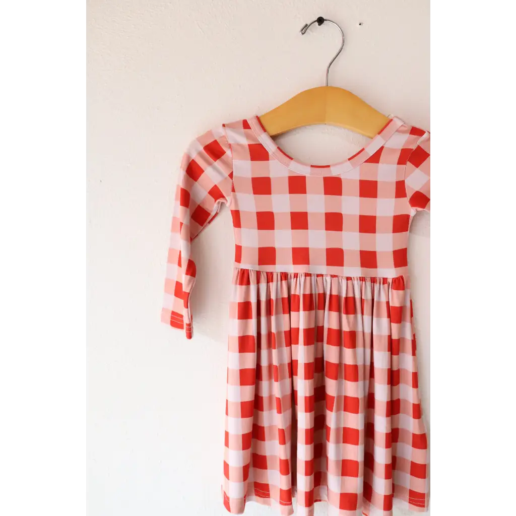 Red and white gingham Kit Plaid Dress for Girls on a wooden hanger, perfect for twirling