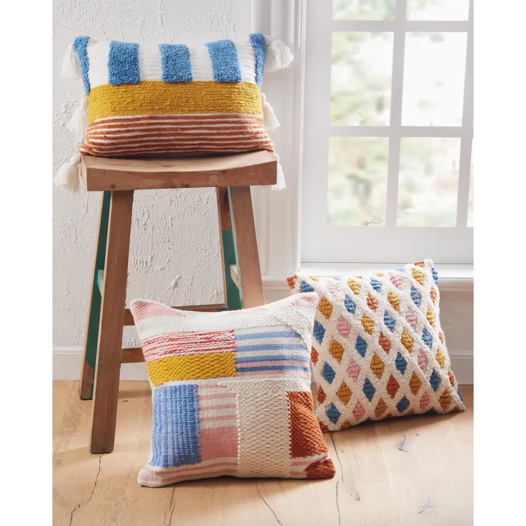 Colorful Lana Decorative Pillows with geometric diamond pattern stacked on wooden stool