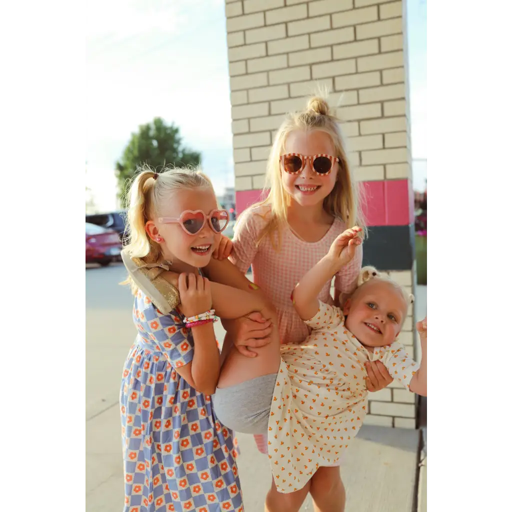 Three happy kids in summer dresses enjoying fun moments in a Lemon Shake Up Twirl Dress