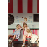 Three kids enjoying playtime in a retro diner while wearing a cute Day Twirl Dress