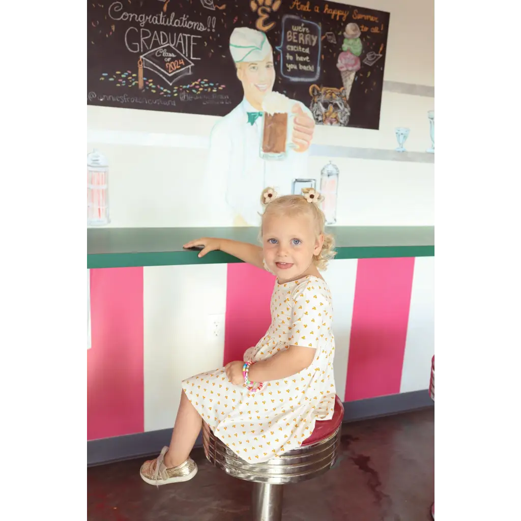 Child on a retro stool in a floral day twirl dress, perfect for fun and style