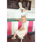 Child on a retro stool in a floral day twirl dress, perfect for fun and style