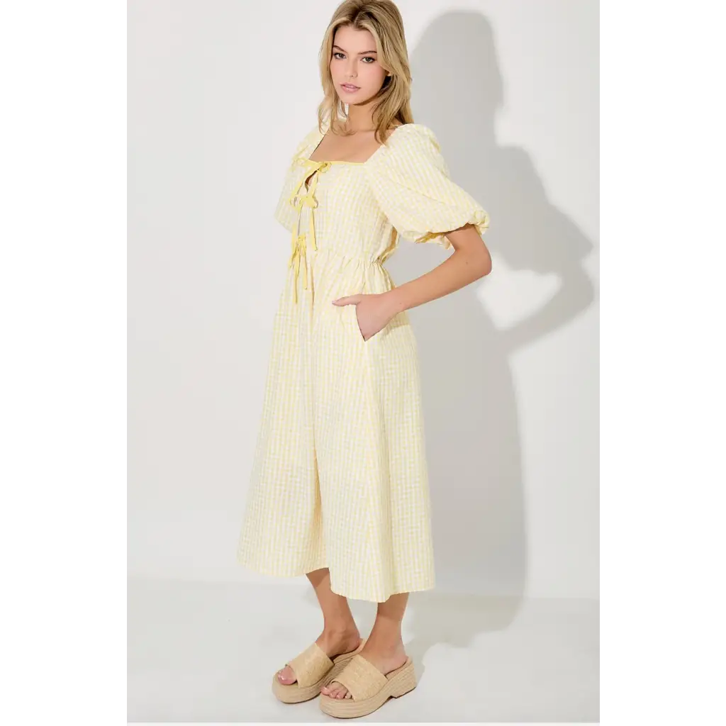 Woman wearing Lemon Meadow Gingham Midi Dress in a yellow gingham midi dress style