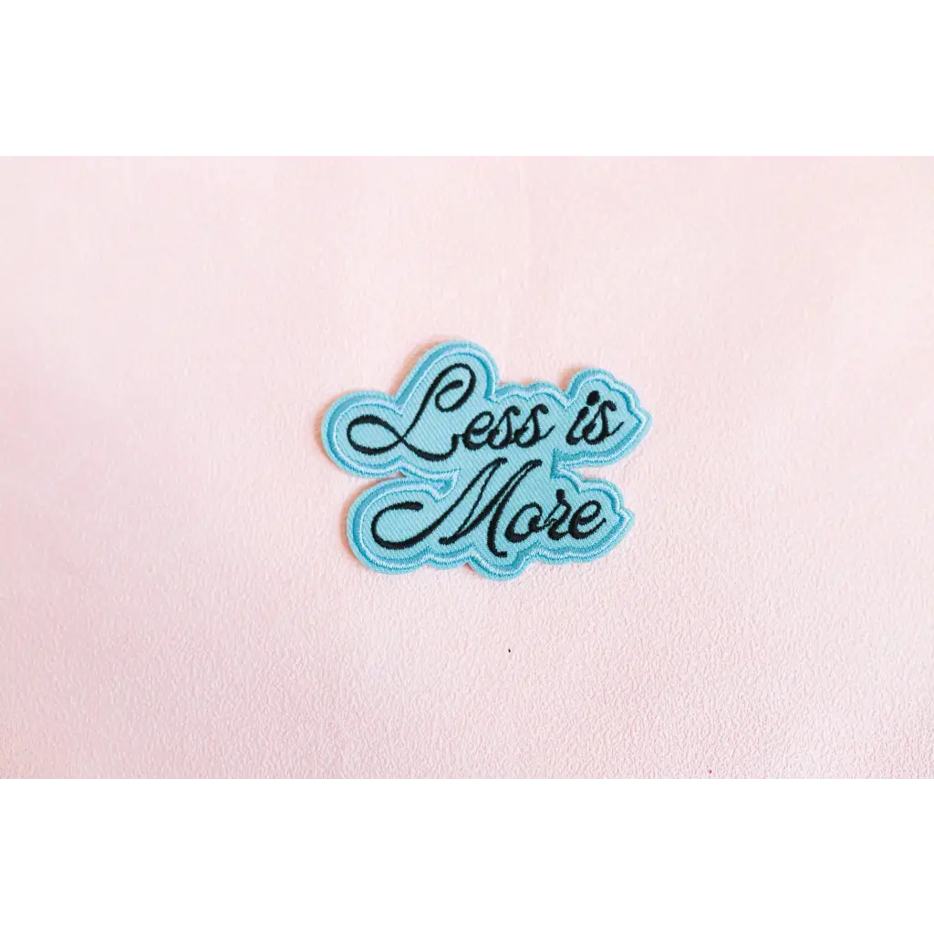 Light blue iron-on patch with cursive Less is More for stylish womens clothes