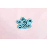 Light blue iron-on patch with cursive Less is More for stylish womens clothes