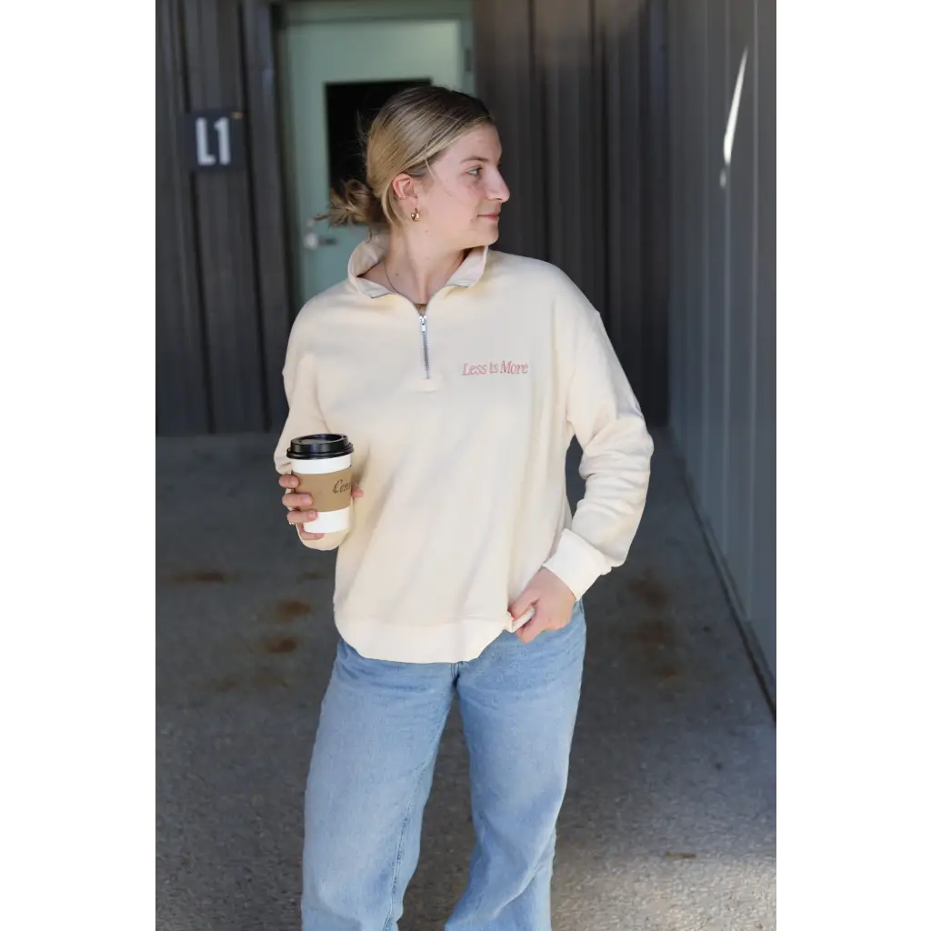 Person in cream embroidered pullover and blue jeans enjoying coffee in style