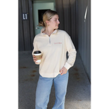 Person in cream embroidered pullover and blue jeans enjoying coffee in style