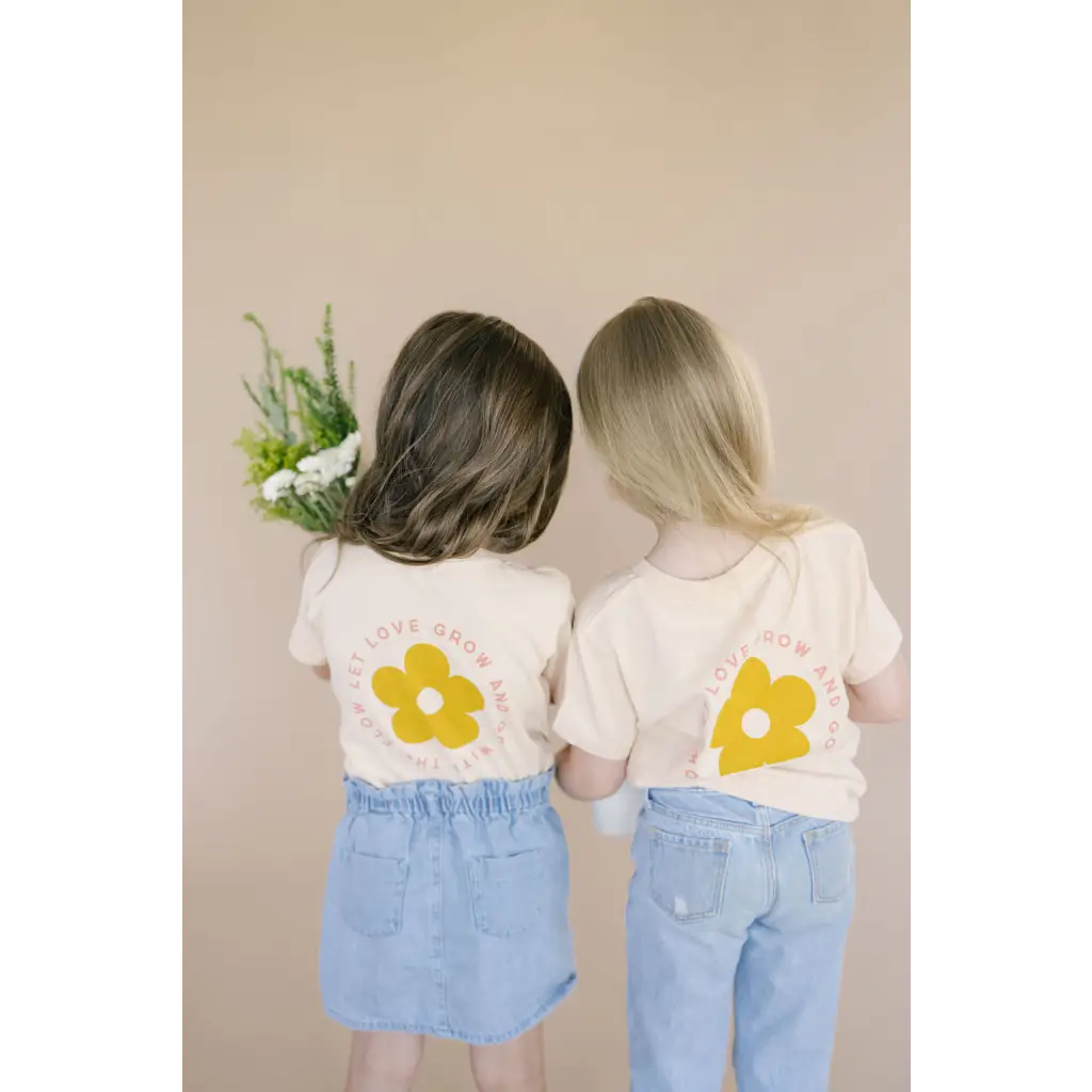 Two kids in matching Let Love Grow graphic t-shirts and denim outfits